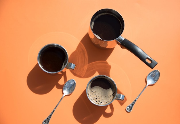 Photo deux tasses de café et de pots sur fond orange lors d'un petit-déjeuner matinal ensoleillé