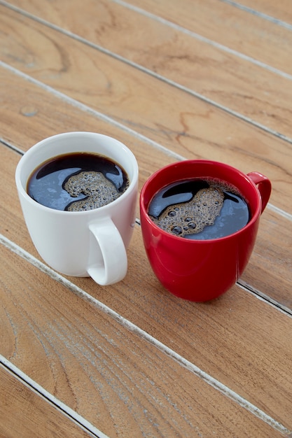 Deux tasses de café rouge et blanc sur bois