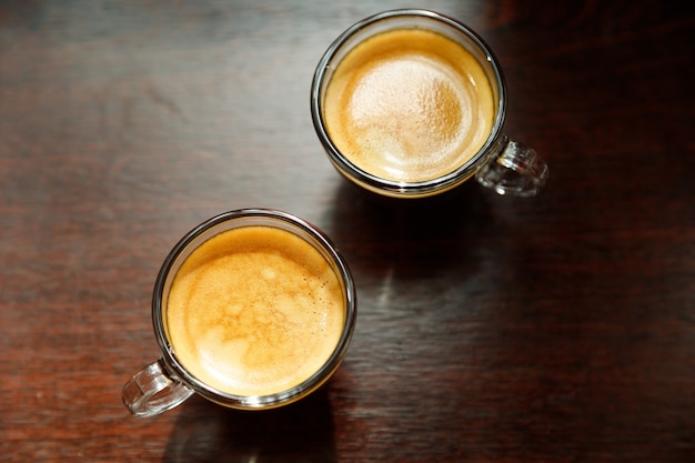 Deux tasses à café en verre avec expresso près de la fenêtre le matin sur fond sombre