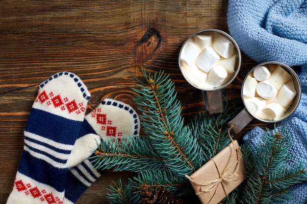 Deux tasses de chocolat chaud ou de chocolat avec des mitaines de guimauve, un décor de Noël et un sapin sur une r...