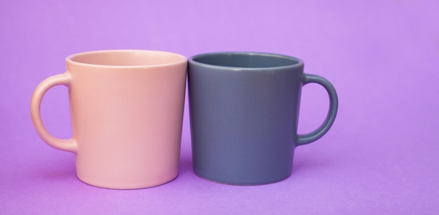 Deux tasses de couleur rose et grise se tiennent sur un fond violet