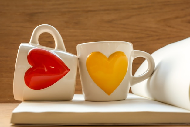 Deux tasses sur le livre avec la forme de coeur rouge et jaune