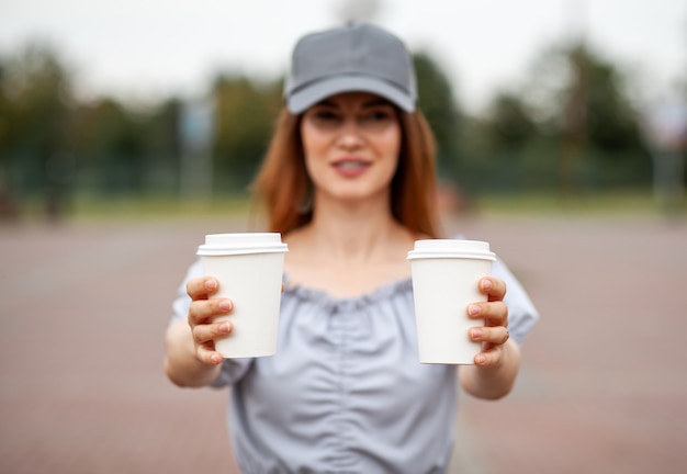 Photo deux tasses en papier blanc avec du café dans la main de la femme. il est temps de boire un café en ville. café à emporter. profitez du moment, faites une pause. gros plan de la tasse de papier jetable. délicieuse boisson chaude. espace vide pour le texte,