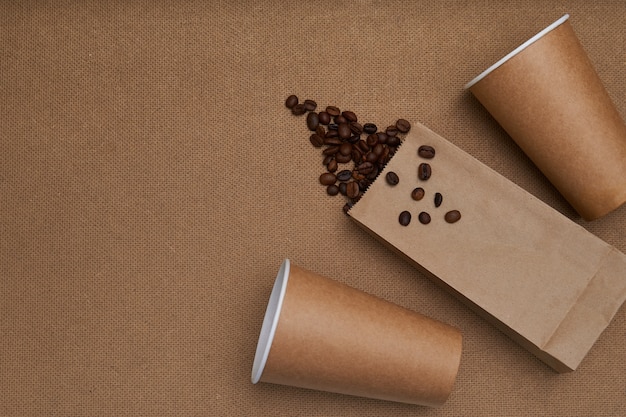 Deux tasses en papier avec des grains de café et un paquet