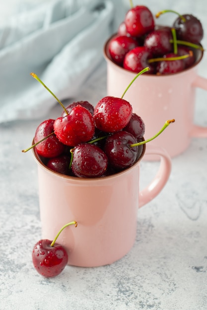 Deux tasses roses avec des cerises mûres fraîches