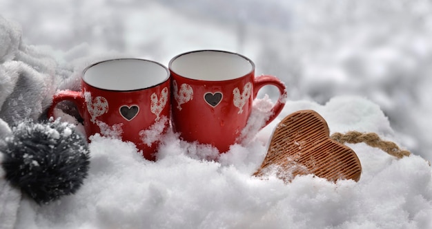 Deux tasses rouges avec coeur en bois en forme sur le concept de la Saint-Valentin de la neige