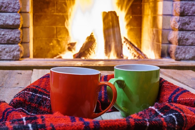 Photo deux tasses à thé ou café, laine près de la cheminée, dans une maison de campagne, hiver