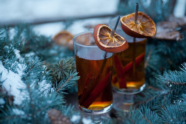 Deux tasses de thé chaud avec de la cannelle et des tranches d'orange dans une couronne de Noël sur un banc en bois