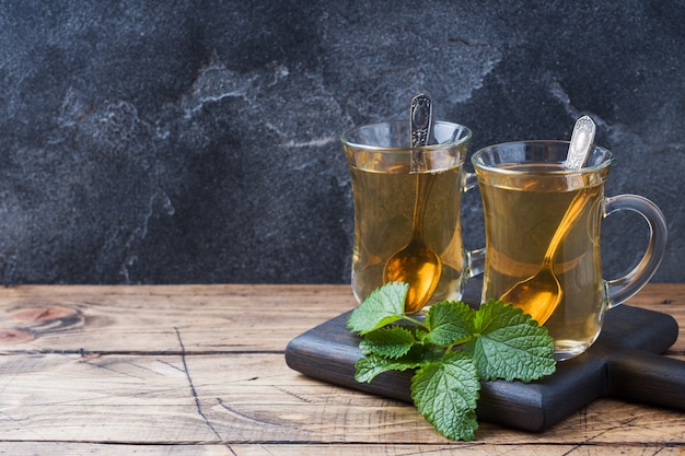 Deux tasses de thé à la menthe sur une surface en bois.