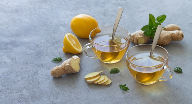 Deux tasses en verre de thé au gingembre avec des citrons et des feuilles de menthe. Espace pour le texte