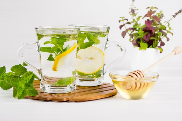 Deux tasses en verre de thé à la menthe fraîche avec du citron et un bouquet de menthe dans un vase