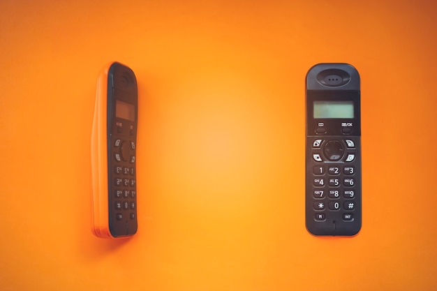 Deux téléphones sans fil sans fil, radiotéléphone, téléphone sans fil dect sur fond orange.