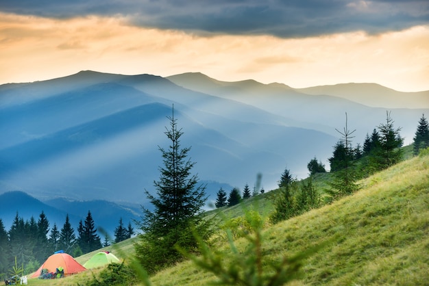 Deux tentes dans un camping avec vue sur les montagnes et le coucher du soleil