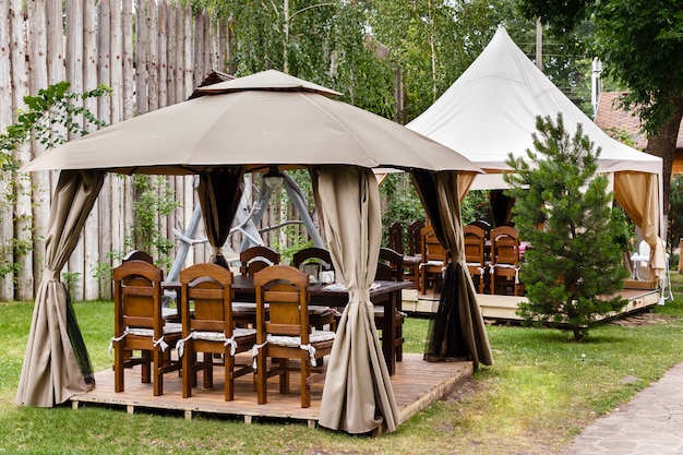 Deux tentes en toile avec des tables et des chaises en bois.