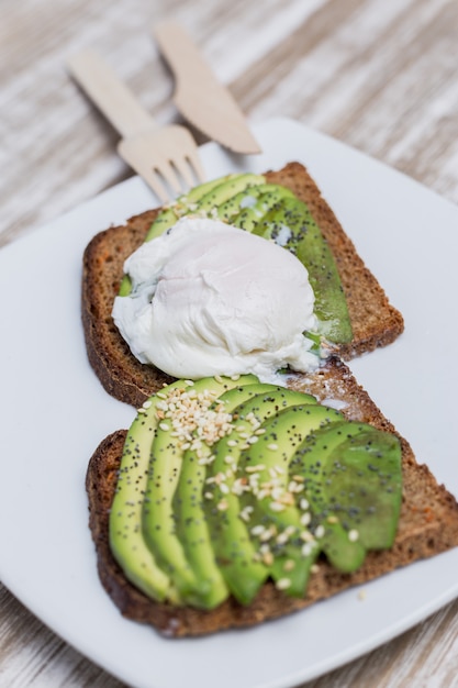 Deux toasts à l&#39;avocat et oeuf sur une table en bois