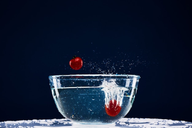 Deux tomates tombent dans la nourriture végétarienne en verre.