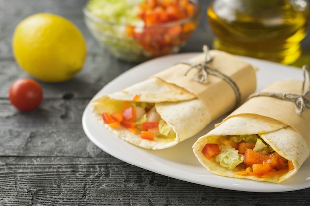 Deux tortilla aux légumes à partir de farine de blé dans un bol blanc sur une table en bois