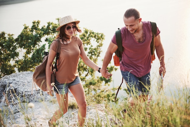 Deux touristes homme et femme avec des sacs à dos montent au sommet de la montagne et profitent du lever du soleil. Concept de vacances aventure voyage lifestyle