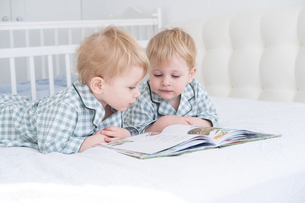 Deux tout-petits bébés jumeaux en pyjama livre de lecture couché