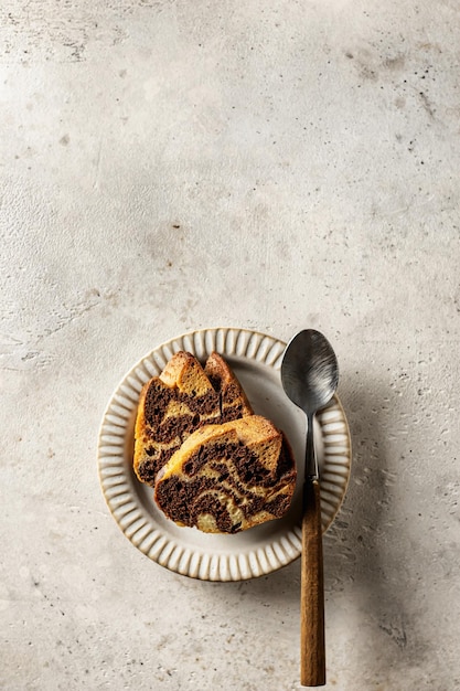 Deux tranches de gâteau zébré sur une assiette avec la cuillère sur fond texturé, vue de dessus, orientation verticale, espace de copie, isolé