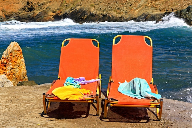 Deux transats rouges sur la plage avec la mer en arrière-plan