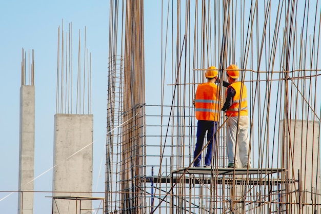 Deux travailleurs de la construction en salopette travaillant sur chantier