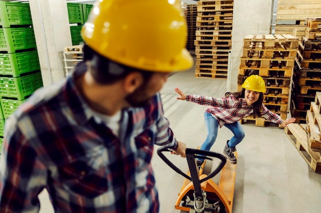 Deux travailleurs s'amusant au travail avec un chariot élévateur