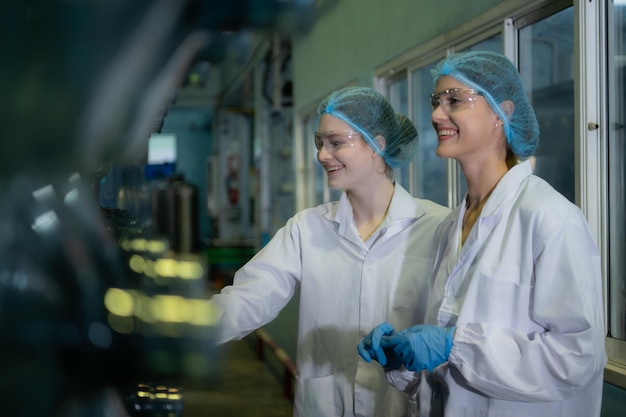 Deux travailleuses en blouse blanche debout à l'usine d'eau potable avec des bouteilles d'eau