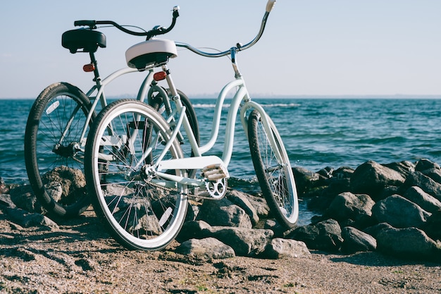 Deux vélos rétro sur la plage contre la mer bleue