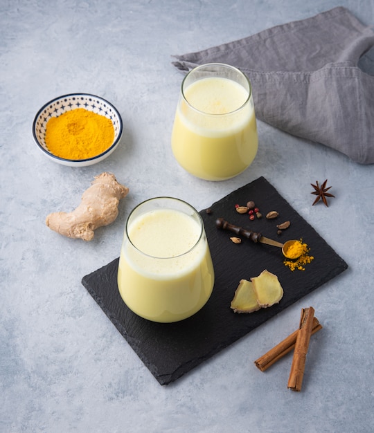 Deux verre de lait doré au curcuma sur fond gris