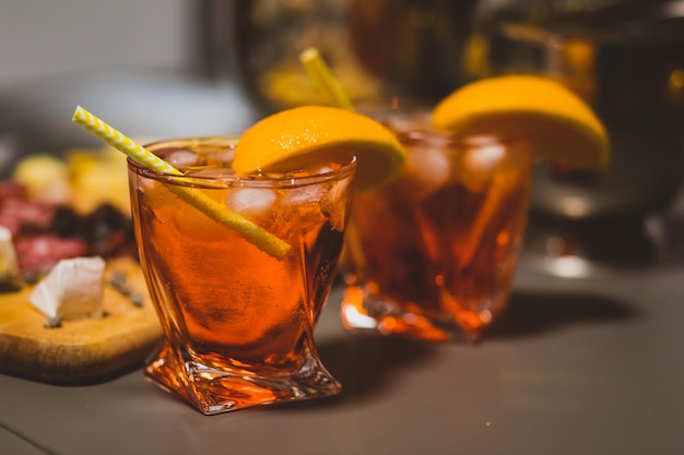 Deux verres d'Aperol spritz avec de petites pailles et des tranches d'orange sur une surface grise Cocktail d'été en automne ou en hiver pour rappeler des souvenirs chaleureux Libre de boissons gazeuses