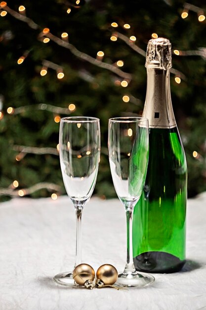 Photo deux verres et une bouteille de champagne sont sur une nappe festive sur la table sur fond de sapin de noël et de lumières