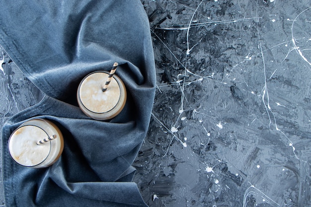 Deux verres de café froid avec du lait sur une surface en marbre.