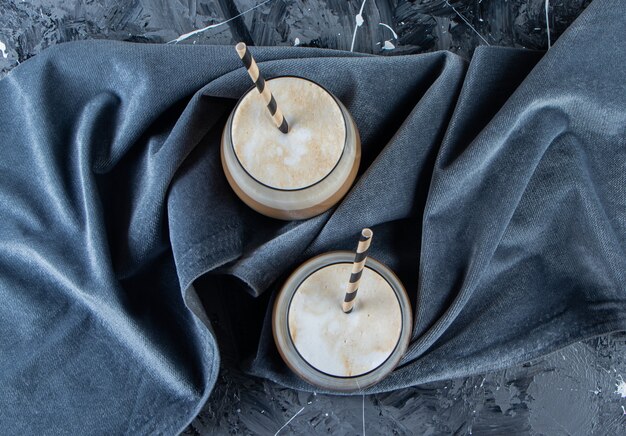 Deux verres de café froid avec du lait sur une surface en marbre.