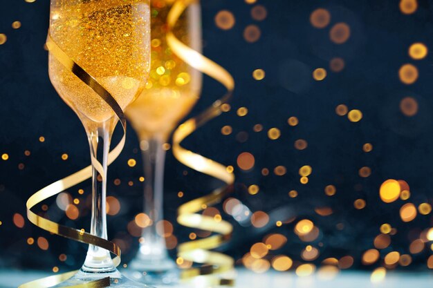 Deux verres de champagne avec des confettis dorés, des serpentins et des lumières.