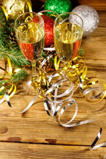Photo deux verres de champagne et décorations de noël festives sur table en bois. fête de noël et du nouvel an