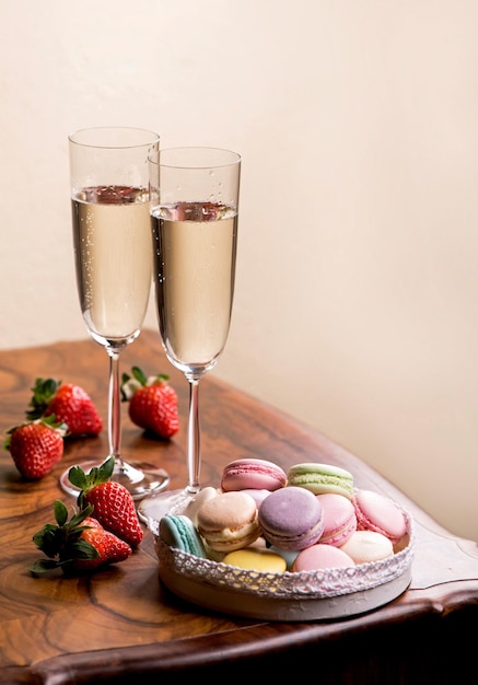Deux verres de champagne et macarons aux fraises sur une table en bois