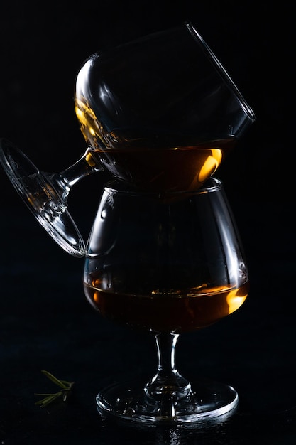 Deux verres à cognac sur fond sombre L'un est placé latéralement sur l'autre