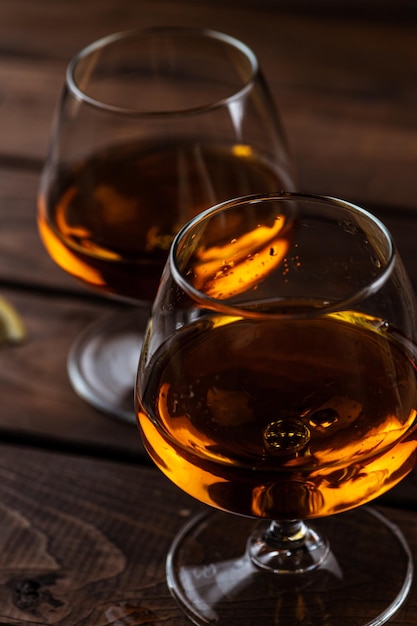 Deux verres de cognac sont sur une table en bois