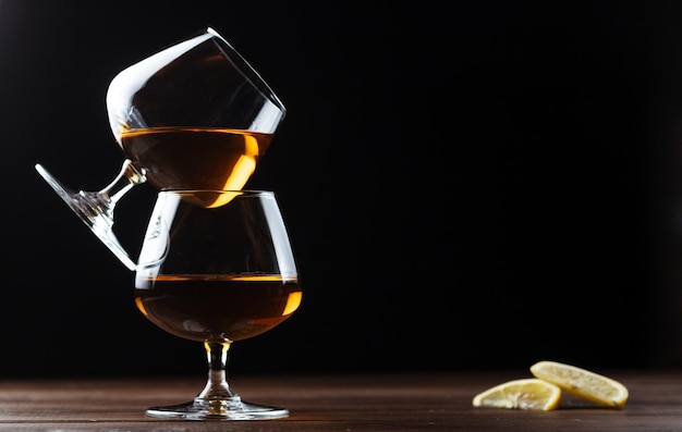 Deux verres de cognac sont sur une table en bois