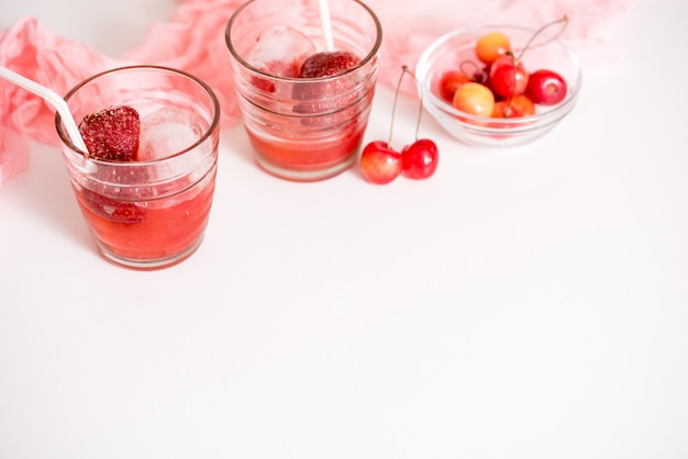 Deux verres avec compote de cerises, cerises sur une assiette, serviette sur un fond en bois rose. Mise au point sélective