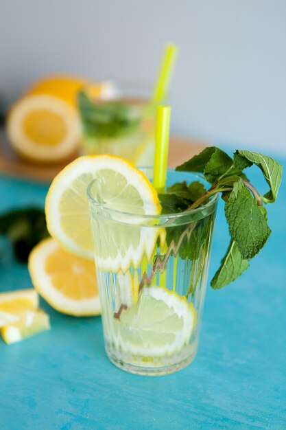 Deux verres avec une délicieuse limonade maison sur fond gris assis sur un bureau bleu