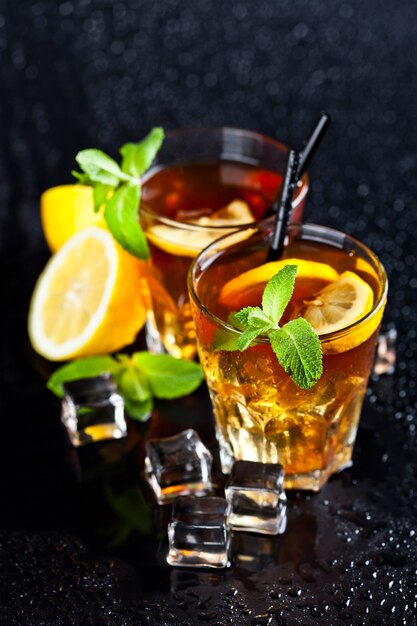 Deux verres avec du thé glacé traditionnel froid avec du citron, des feuilles de menthe et des glaçons.