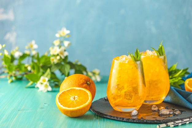Deux verres de glace à l'orange avec de la menthe fraîche sur la surface de la table en bois turquoise