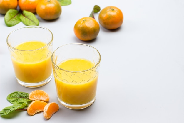 Deux verres de jus d'agrumes. Mandarines sur table.