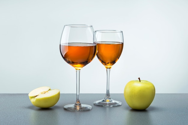 Deux verres de jus de pomme avec des pommes de fruits sur une surface grise. Concept de nourriture saine.