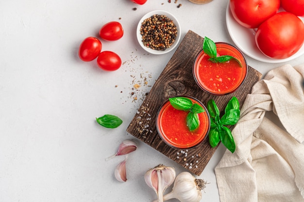 Deux verres de jus de tomate sur fond gris avec des ingrédients