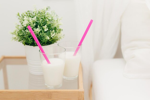 Deux verres de milkshake à la vanille sur la table de chevet pour le petit déjeuner vase de plante verte près de boissons fraîches avec des pailles dans la chambre de délicieux cocktails