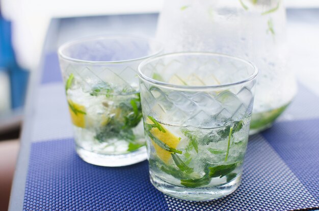 Deux verres pleins d'eau fraîche fraîche transparente avec de la glace, du citron et des feuilles de basilic