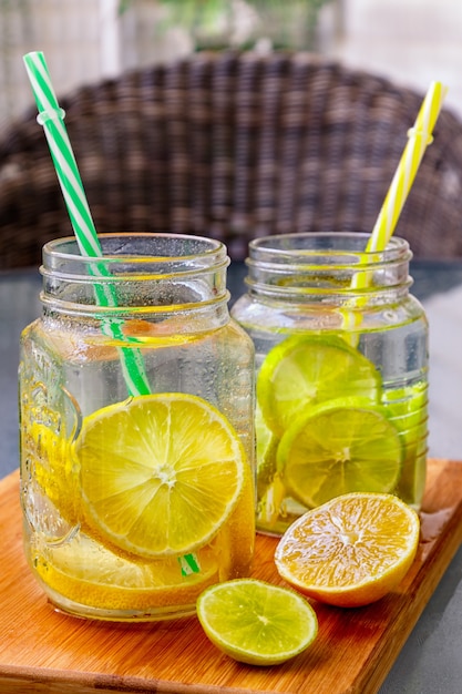 Photo deux verres de pot mason de limonade maison avec une partie de citrons sur une planche à découper en bois